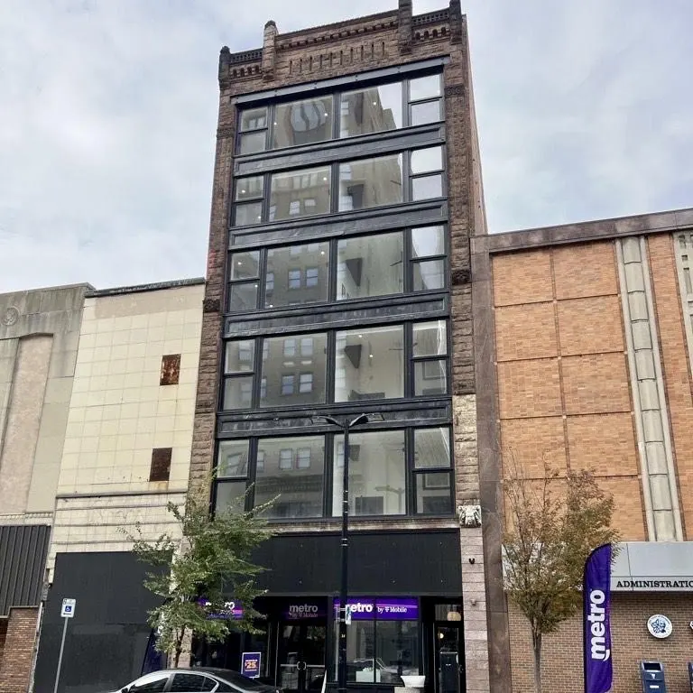 six-story brick and glass storefront building on a downtown block